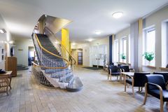 Valoisa aula, jossa on tiililattia, portaat ja istuimia.