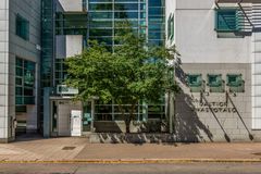 Moderni rakennus, jossa on lasijulkisivu ja vihreä puu edustalla.