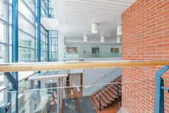 Moderni julkinen rakennus, jossa on suuret ikkunat, punatiilinen seinä ja portaikko.