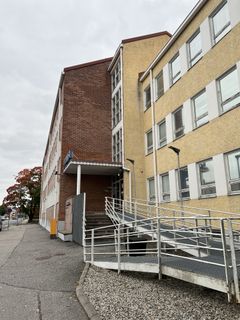 Virastotalo, jossa on tiili- ja vaaleanruskea seinä sekä pyörätuoliramppi.