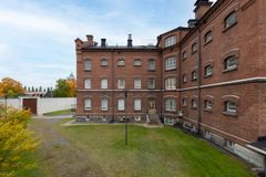 Tiilirakennus, jossa on useita kerroksia ja klassisia arkkitehtonisia yksityiskohtia, ympäröitynä nurmialueella.