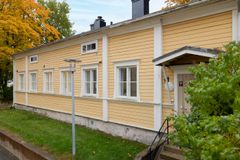 Keltainen, puurakenteinen talo, jossa on valkoisia ikkunanpieliä, sijaitsee rauhallisella kadulla.