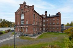 Punatiilinen, kolmikerroksinen historiallinen rakennus, ympärillä puutarha ja syksyinen maisema.