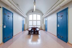 Käytävä, jossa on siniset ovet ja puinen penkki ikkunan alla.