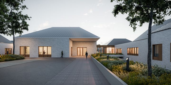 Uudisrakennuksen sisäänkäynnin havainnekuva iltavalaistuksessa.