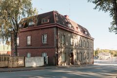 Vanha punatiilinen rakennus kulmassa, jossa on ruskea katto ja useita ikkunoita. Kadun ympäröimänä.