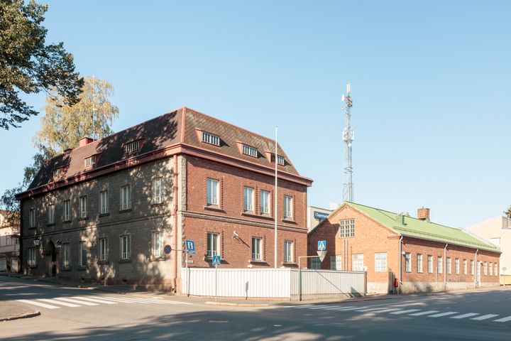 Vanha tiilirakennus kadunkulmassa, ja taustalla telemasto.