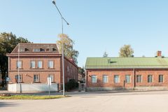 Tiilirakennukset kirkkaassa päivänvalossa. Yksi rakennuksista on viistokattoinen ja toinen loivakattoinen.