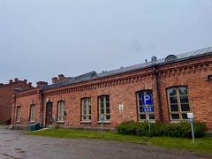 Tiilirakennus, jossa on pyöreitä ikkunoita. Edessä on pysäköintikyltti ja osa nurmialuetta.