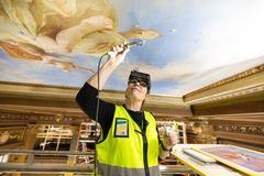 Konservaattori työskentelee koristellun kattomaalauksen parissa Säätytalossa.