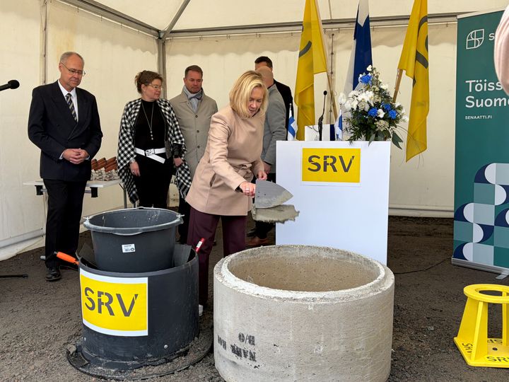 Sisäministeri Mari Rantanen muuraa peruskiveä rakennustyömaalla.