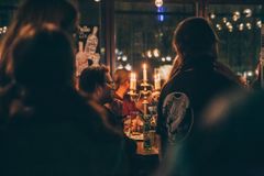 Hämärä valaistus täydessä baaritilassa, pöydällä kynttilöitä, ihmiset kuuntelevat.