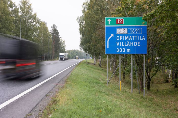 Valtatiellä 12 rekka. Tien laidassa opastekyltti Villähde, Orimattila.
