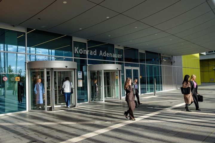 Seitsemän ihmistä kulkemassa Euroopan parlamentin rakennukseen ja ulos rakennuksesta Luxemburgissa.