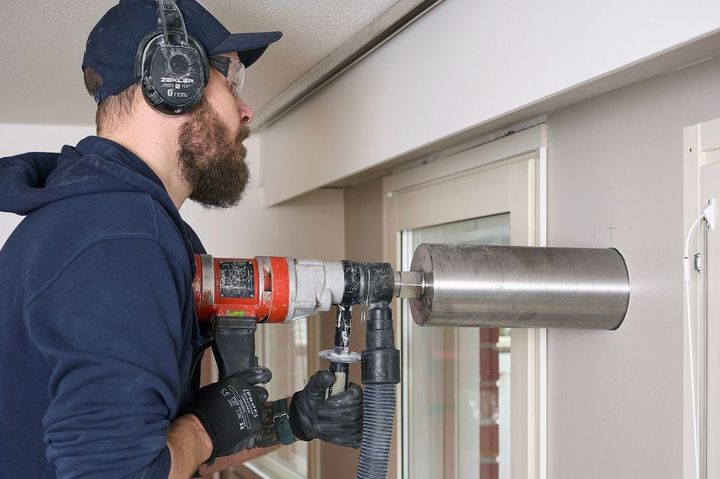 Mies tekee läpivientiä seinään timanttiporalla.