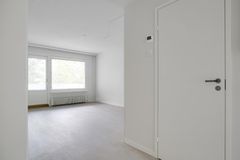 Olohuone, jossa on valkoiset seinät ja suuret ikkunat.