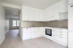 Alt teksti: Moderni, vaaleasävyinen keittiö, jossa on valkoiset kaapistot ja harmaa työtaso.