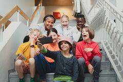Lapsia istumassa koulun portaikossa ja ottamassa kuvaa älypuhelimella.