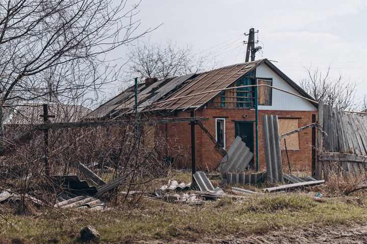 Kuvassa on vanha, rapistunut tiilirakennus, jossa on osittain romahtanut katto. Rakennuksen ympärillä on rikkinäisiä aitoja ja romua.