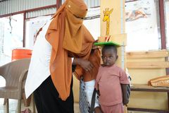 Hoivava työntekijä mittaa lapsen pituutta terveysklinikalla Gedarefin osavaltiossa, Sudanissa. Lapsella on vihreä alusta päänsä päällä.