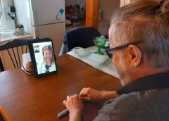 Henkilö keskustelee videoyhteydellä hoitajan kanssa kotonaan pöydän ääressä istuen.