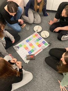 Nuoria kokoontuneena lattialle pelin äärelle.