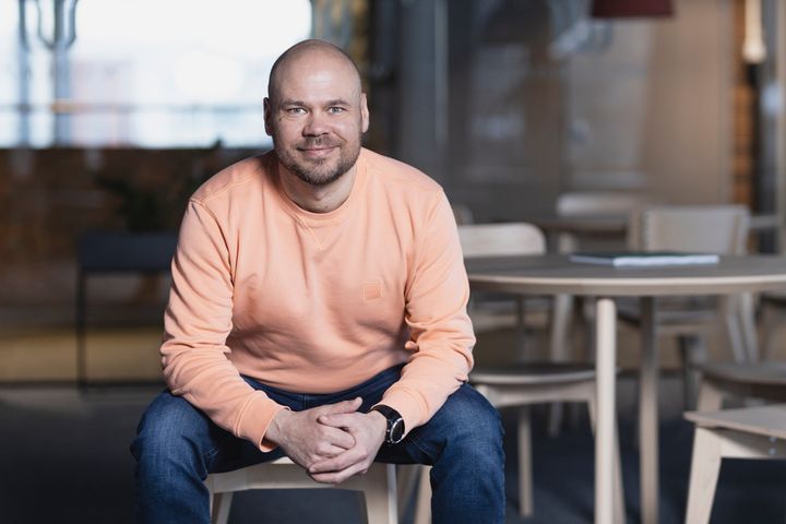 EnCoHubin toimitusjohtaja Jan Landén istuu rennosti sisätiloissa pöydän ääressä, pukeutuneena oranssiin collegepaitaan ja farkkuihin.