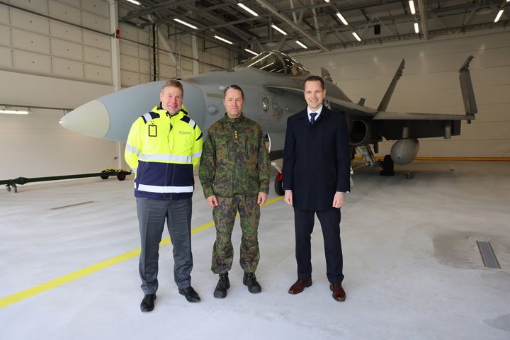 Kuvassa ovat vasemmalta alkaen Puolustuskiinteistöjen toimitusjohtaja Matias Warsta, Karjalan lennoston komentaja eversti Tomi Böhm ja F-35-hankejohtaja eversti evp. Henrik Elo. Taustalla Ilmavoimien Hornet-hävittäjä.