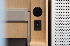 Kuvassa näkyy sänkykaluste, jossa on pieni hylly ja pistorasia.