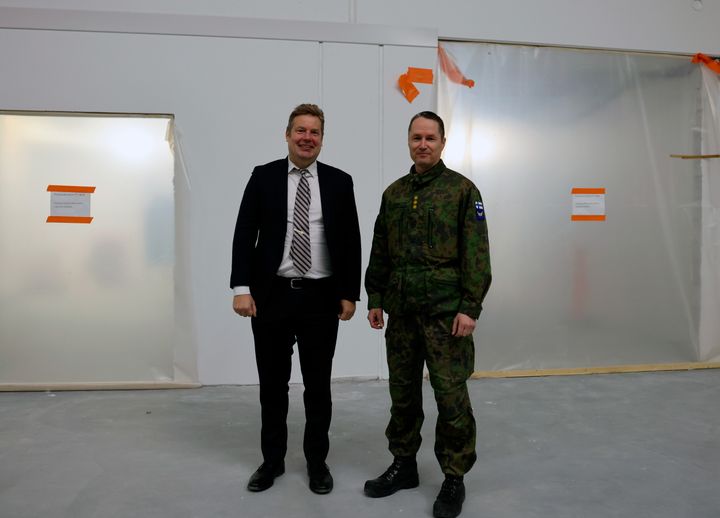 Tilaisuudessa Puolustuskiinteistöjen toimitusjohtaja Matias Warsta ja Karjalan lennoston komentaja eversti Tomi Böhm seisovat yhdessä hymyillen materiaaliterminaalin rakennustyömaalla.