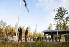 Sotilaat nostavat Suomen lipun salkoon ulkona metsäisessä ympäristössä.