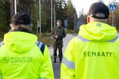 Henkilö seisoo ulkona puhumassa kahdelle neonkeltapukuiselle henkilölle.
