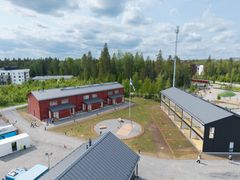 Ilmakuva punaisesta ja mustasta rakennuksesta vehreällä alueella.