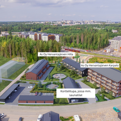 Ilmakuva uudesta asuinalueesta metsän keskellä, rakennuksia ja pitkiä teitä näkyvissä.