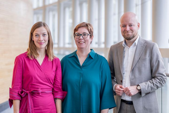 Vasemmistoliiton mepit Li Andersson, Merja Kyllönen ja Jussi Saramo seisovat rivissä vierekkäin ja hymyilevät.