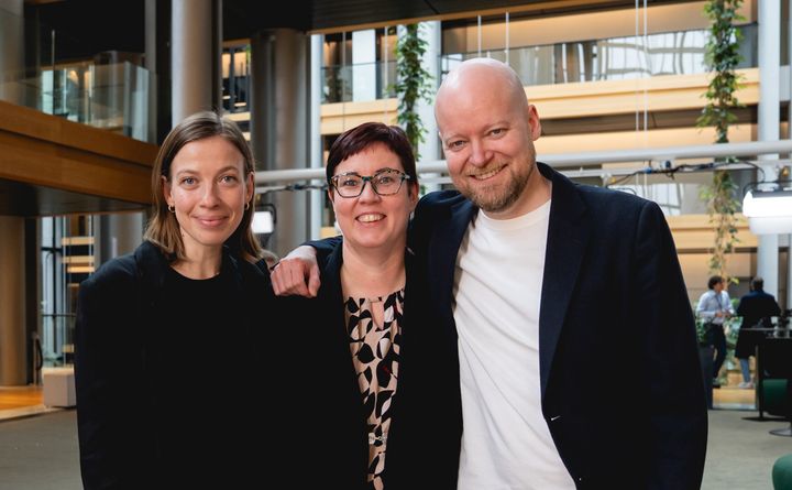 Vasemmistoliiton mepit Li Andersson, Merja Kyllönen ja Jussi Saramo seisovat vierekkäin hymyillen leveästi.