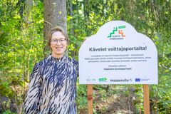 Maa- ja metsätalousministeri Sari Essayah kuntoporraskisan voiton kunniaksi pystytetyn kyltin äärellä.