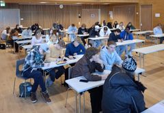 Joukko opiskelijoita istuu luentosalissa keskustelemassa.