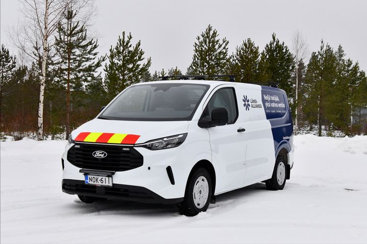 Pakettiauto, jossa on Länsi-allianssin logo ja väritys, seisoo lumisella tiellä.