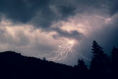 Salamaniskuja tummaa taivasta vasten yöllä, puita siluettina etualalla.