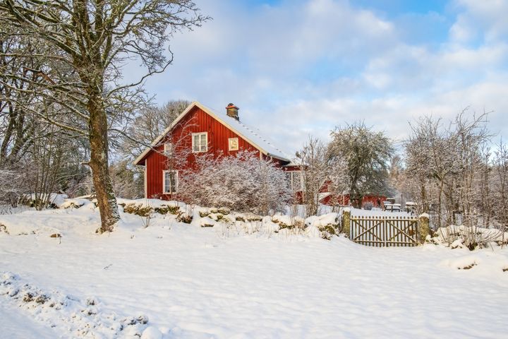 Punainen talo talvisessa maisemassa, lumi peittää maan ja puut.