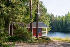 Punainen kesämökki järven rannalla