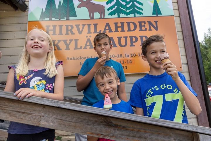 Neljä lasta syö jäätelöä Hirvilahden kyläkaupan edustalla.
