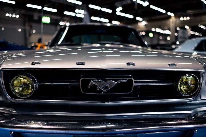 Hopea Ford Mustang auton keula, jossa on kuuluisa hevoslogo, pysäköitynä sisätiloissa.