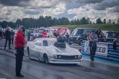 Drag racing auto valmiina lähtöön radalla, henkilökuntaa vieressä.