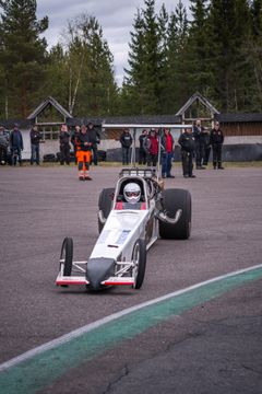 Henkilö ajaa kilpa-autolla radalla kohti lähtöaluetta.