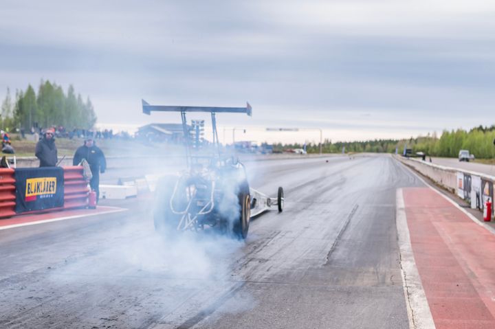 Dragster auto kiihdytysradalla, pakokaasua näkyvissä.