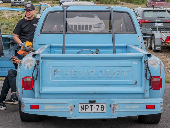 Henkilö sinisen Chevrolet-katuauton vieressä Vesivehmaan katupäivässä.