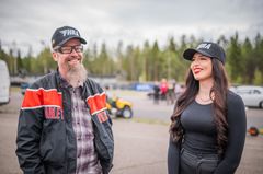 Kaksi henkilöä katselee toisiaan hymyillen kilparadalla, yllään FHRA-lippikset.