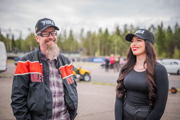 Kaksi%20henkil%F6%E4%20katselee%20toisiaan%20hymyillen%20kilparadalla%2C%20yll%E4%E4n%20FHRA-lippikset.